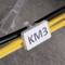 Two yellow cables with a shield displaying 'KM3', with a blurred background.
