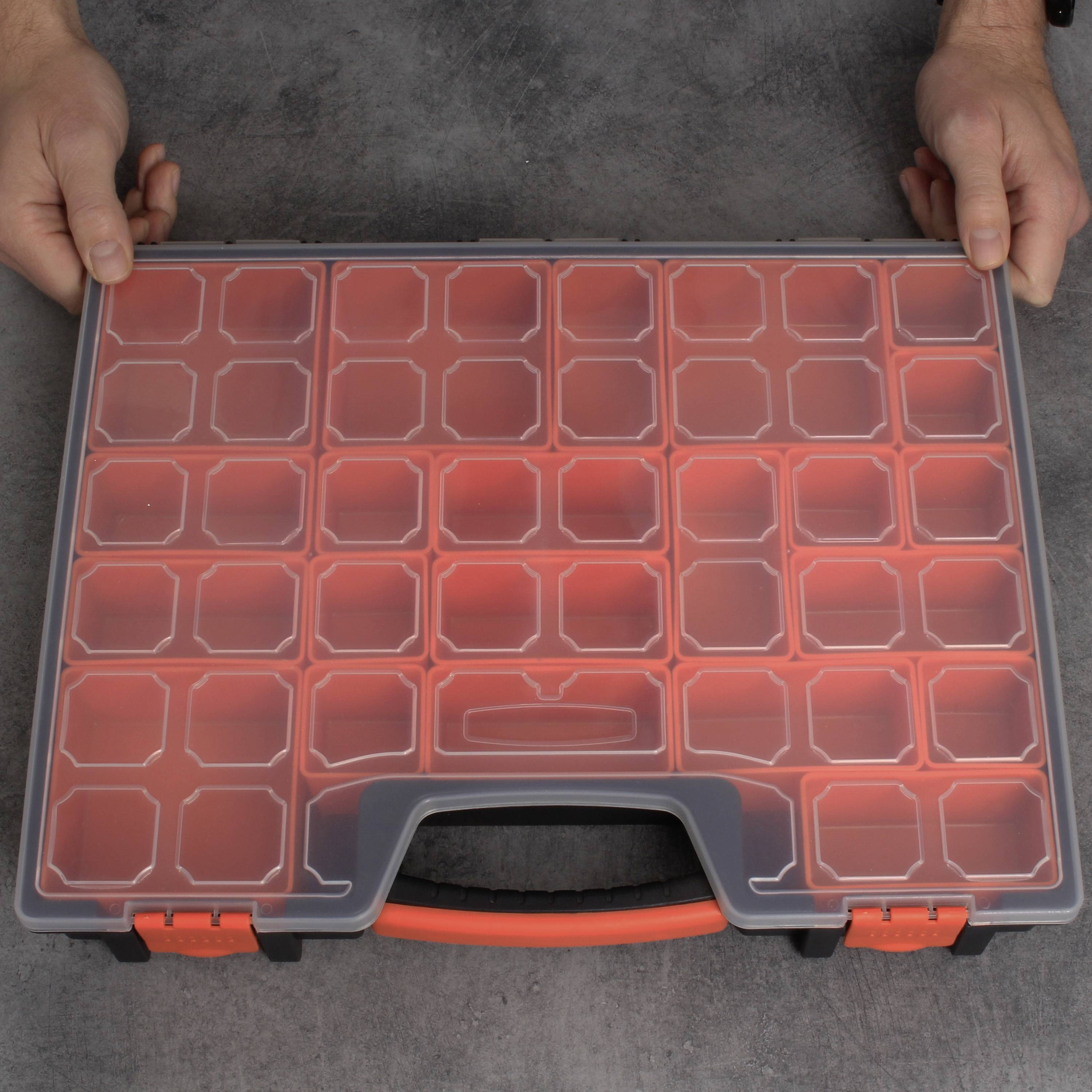 An opened grey toolbox with a transparent lid and several empty compartments. Two hands are holding the box at its sides.
