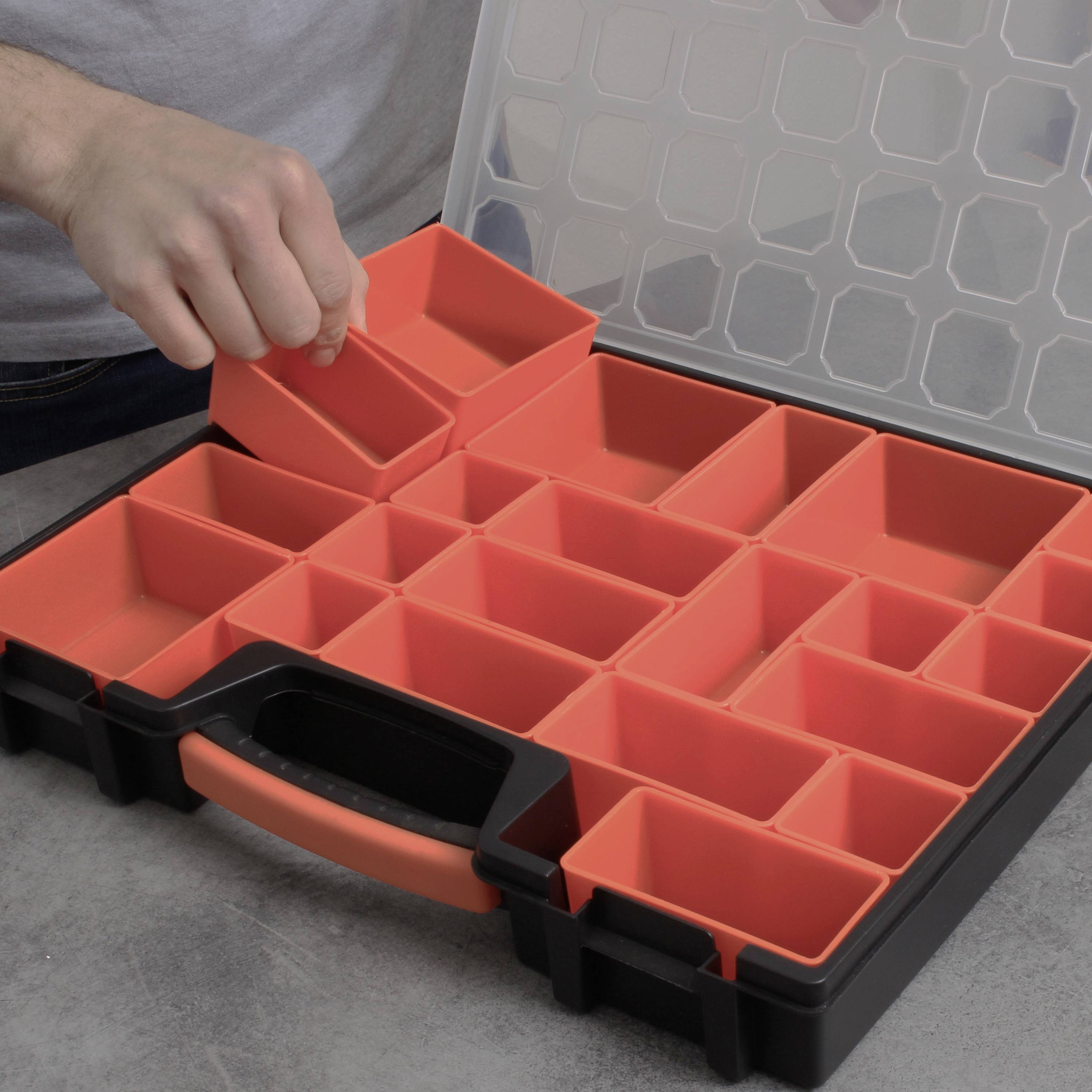 A person places a small, red compartment into a storage box with multiple compartments. The box has a transparent lid.