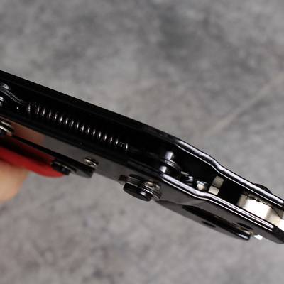 Close-up of a black hinge with visible feathers and screws on a grey surface.