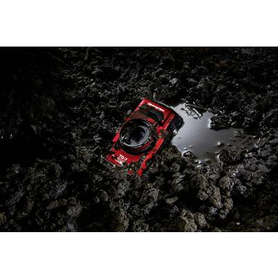 A red and black graphics card lies on a dark, muddy surface, partially surrounded by water.