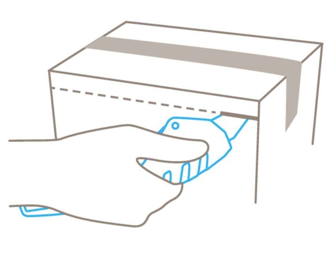 A hand is using a Stanley knife to open a cardboard box along the top edge. The cardboard shows a dotted cutting line.
