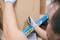 A person carefully opens a cardboard box with a utility knife on a storage shelf, with protective gloves visibly worn.