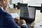A man is analysing a financial chart with lines and curves on a laptop in an office, with documents lying beside him.