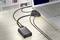 A laptop on a table, connected with multiple cables, including an HDMI cable connected to an HDMI adapter.
