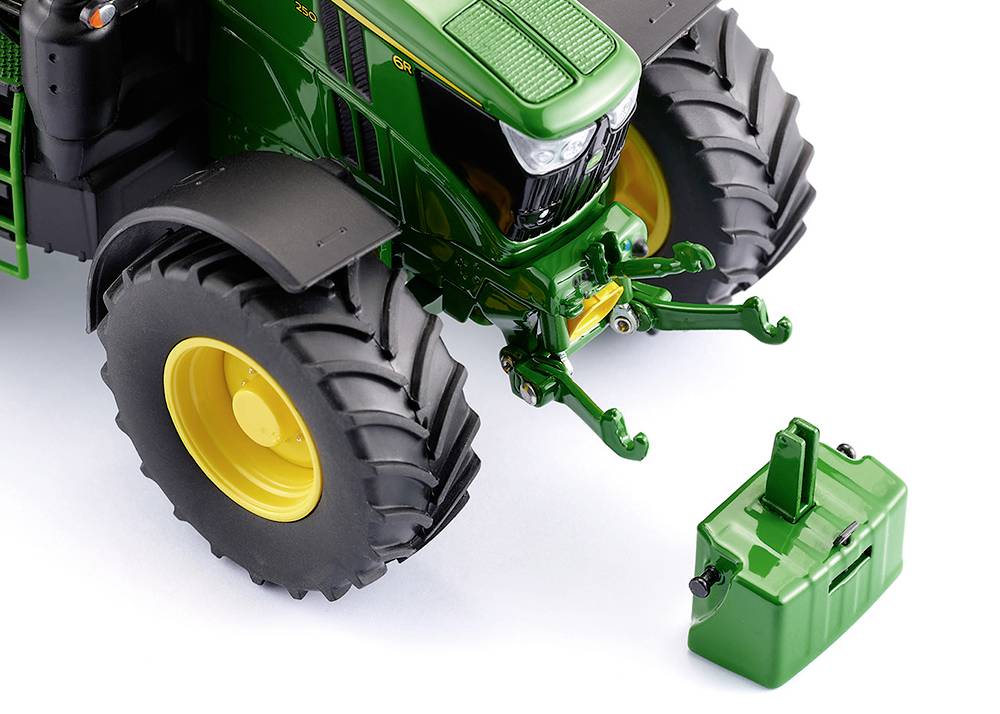 A green tractor with large tyres stands on a white background. A green counterweight lies in front of the vehicle.