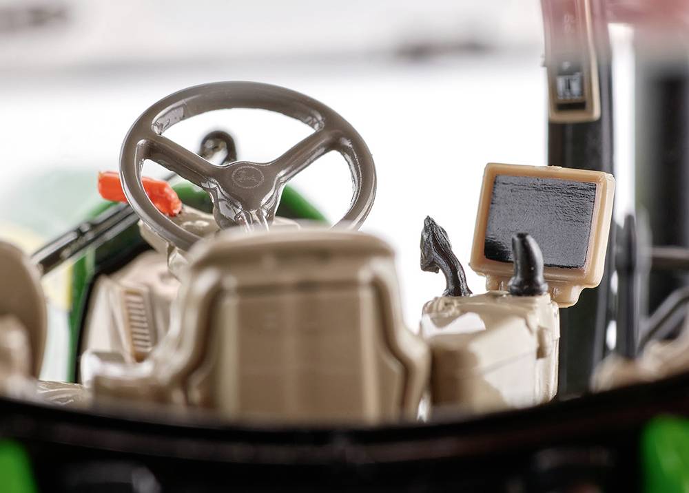 A glimpse into the cockpit of a toy tractor, featuring a steering wheel, seat, and small display; a detailed view of the interior.