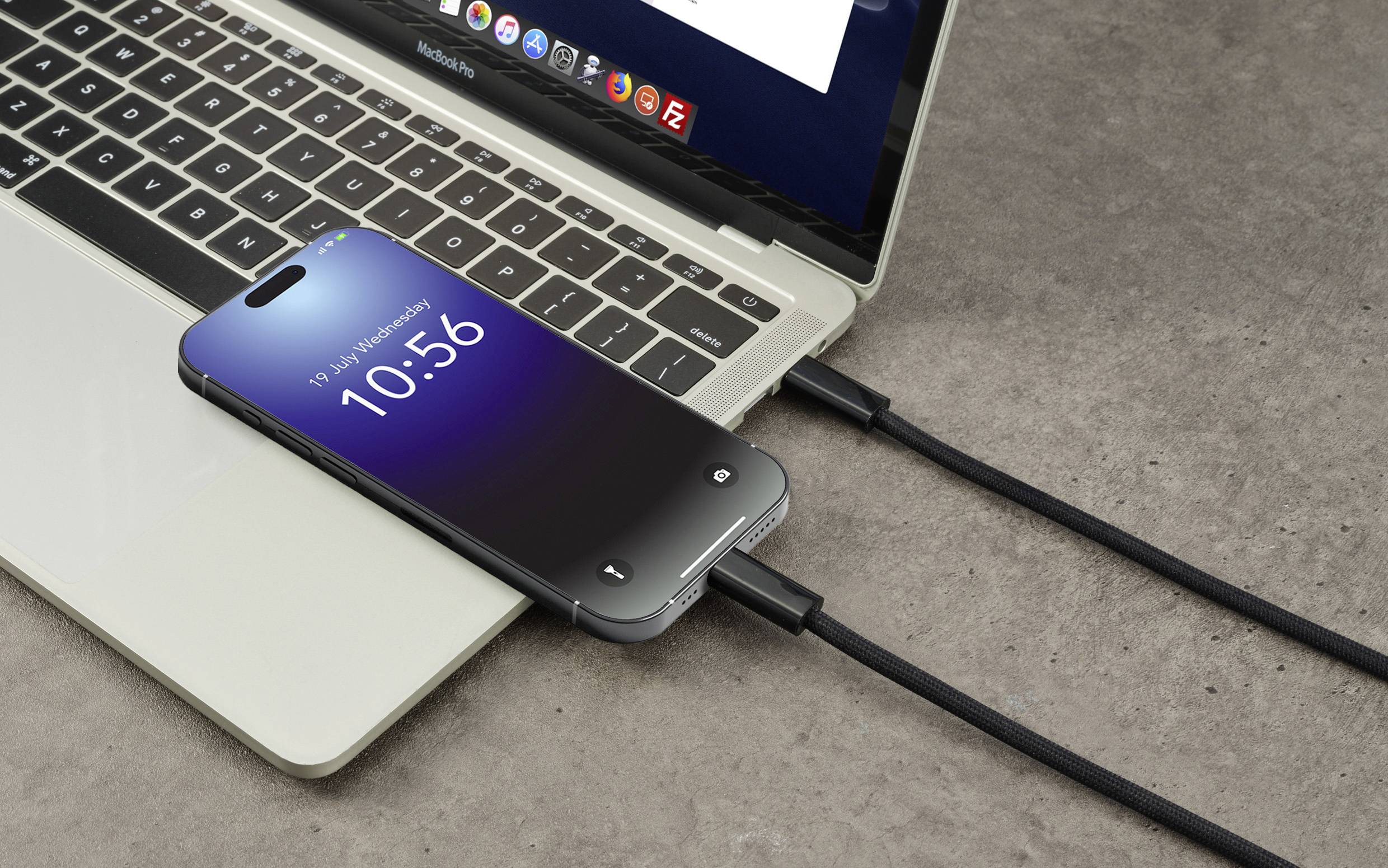 A smartphone is connected to a laptop via a black cable. The phone screen displays the time '10:56'.