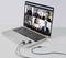 A laptop displays a video call with six people in a virtual meeting. Headphones are connected.