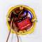 'Close-up of a Shelly 1PM Mini relay, installed in a yellow wall socket, with visible wiring. Label shows specifications.'