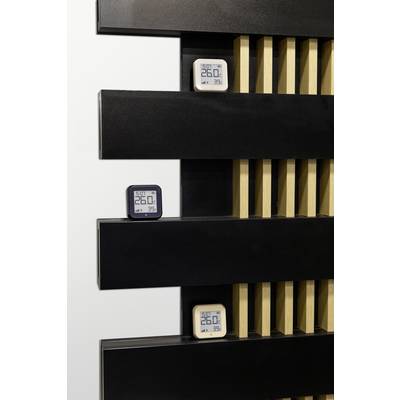 Three digital thermometers and hygrometers are mounted on a modern black and wood-coloured wall. They display 26.0°C and 39% humidity.