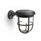 Black, solar-powered outdoor wall light with mesh cover enclosing a bulb, mounted on a grey wall bracket.