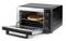 A black and silver mini oven with an open door, where a pizza is being baked on a wire rack. Three rotary knobs on the side.