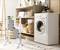 Utility room with a washing machine, shelving with towels and a basket. A clothes airer with towels is positioned in the foreground.