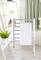 A towel hangs on a towel rail in a room with plants and shelves, on which shoes and a box are placed.