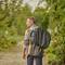 A man with a rucksack is walking along a woodland path. Trees and plants surround the trail. It is a relaxed walk in nature.