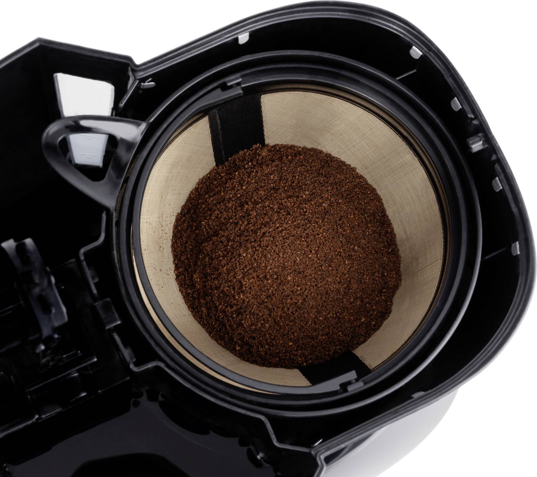 Coffee filter in a coffee machine, filled with freshly ground coffee powder. A top-down view shows the circular arrangement of the beans.