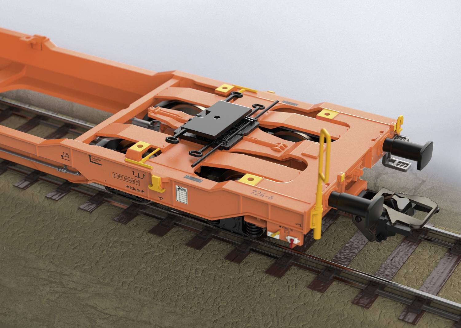 An orange railway wagon frame with a coupling element, positioned on tracks, reveals construction details.