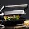 Sandwich toaster with a closed lid, toasting a sandwich with salad and mushrooms, with half a toasted cheese sandwich beside it.