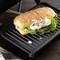 A crispy, grilled sandwich with chicken, lettuce and onions sits on a tabletop grill.