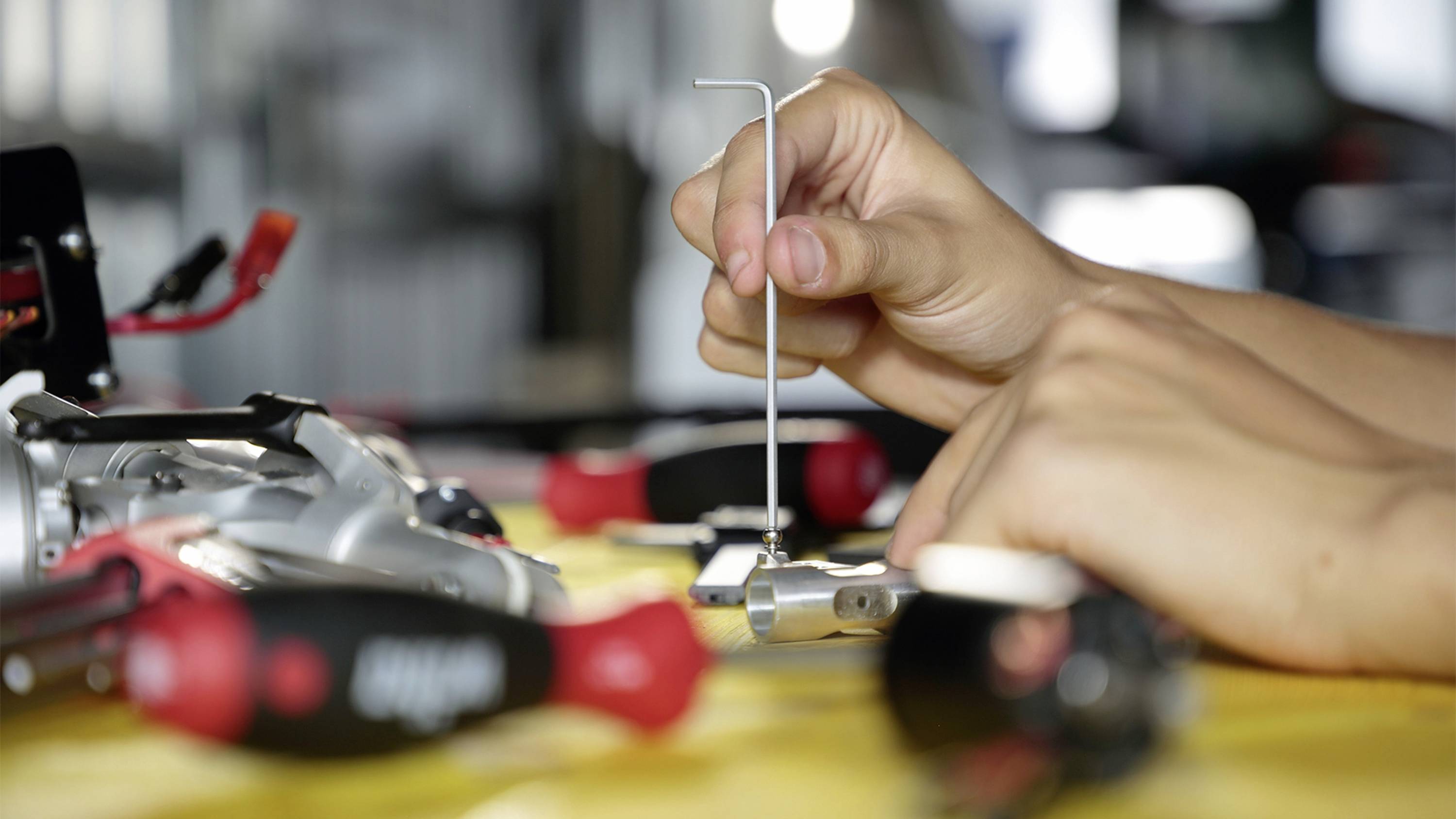 Someone is using an Allen key to work on a mechanical device, surrounded by various tools.
