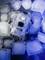 An electronic device in a transparent casing lies between ice cubes. It is illuminated by blue light.