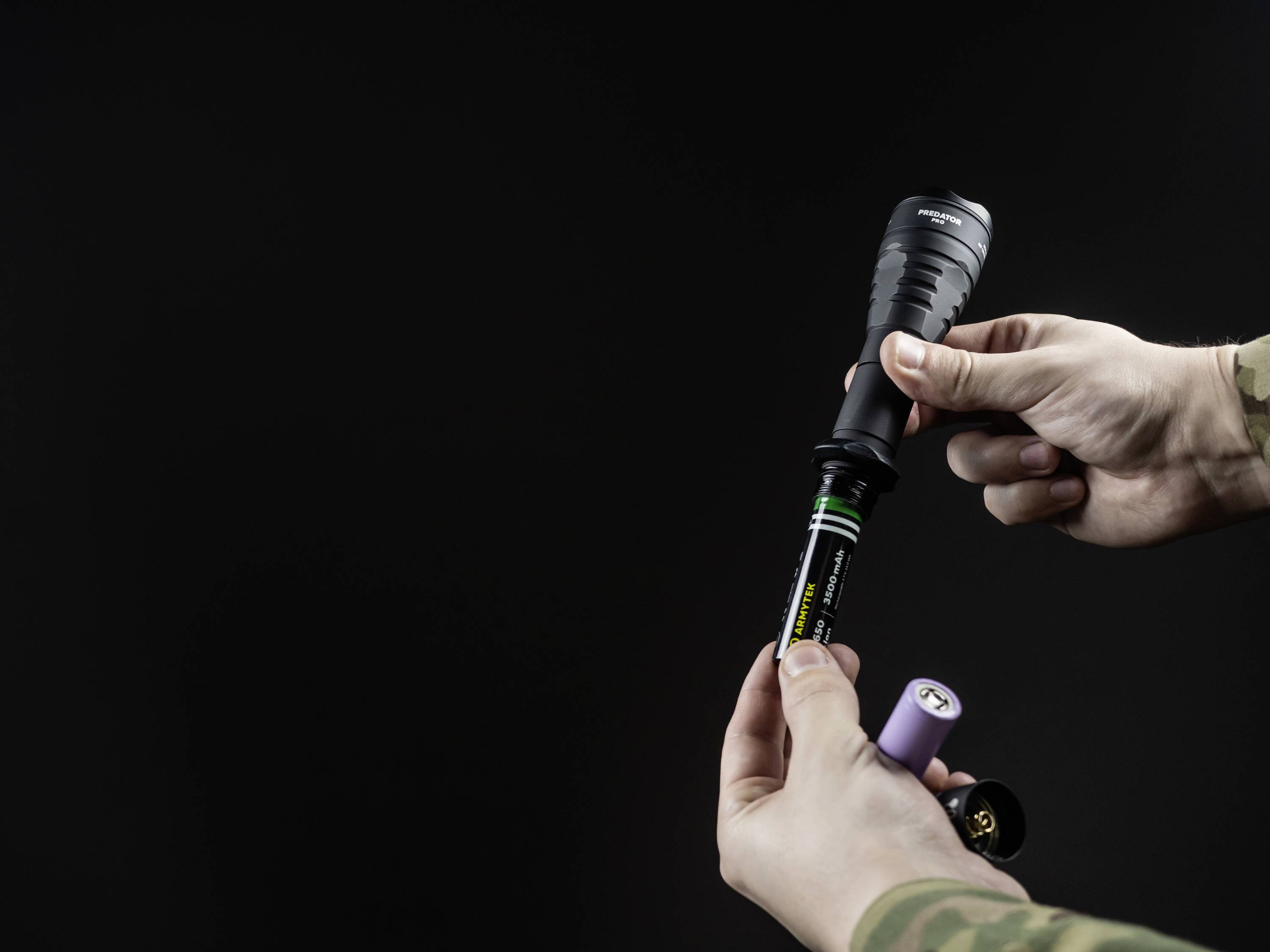 A person is changing the batteries of a torch. The background is black.<br><br>Note: In British English, "flashlight" is typically called a "torch", which is the translation I've used here.