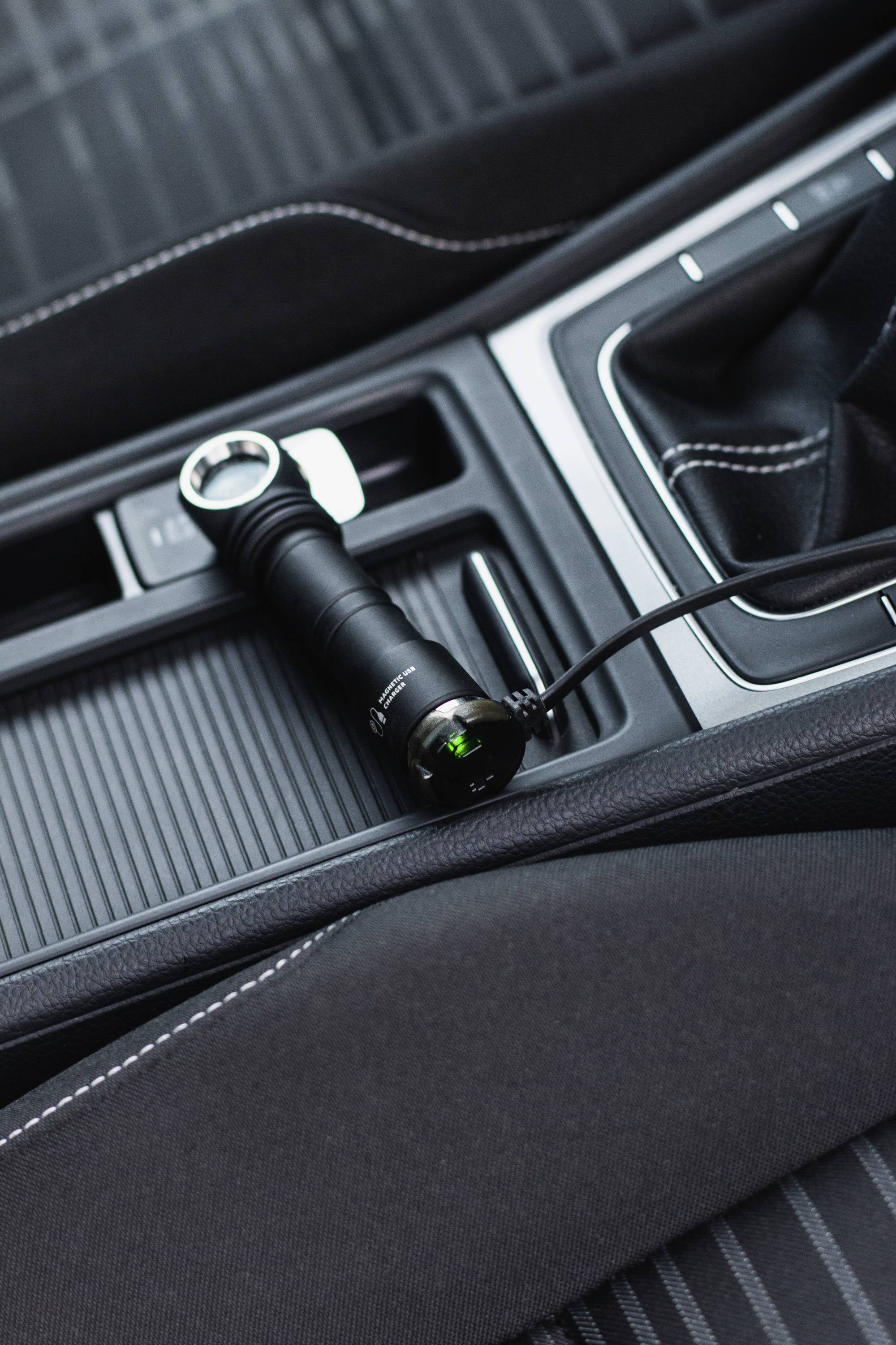 Torch charging via a USB port next to the gear stick in a car.