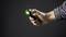 A hand holds a torch with green light, against a dark background.