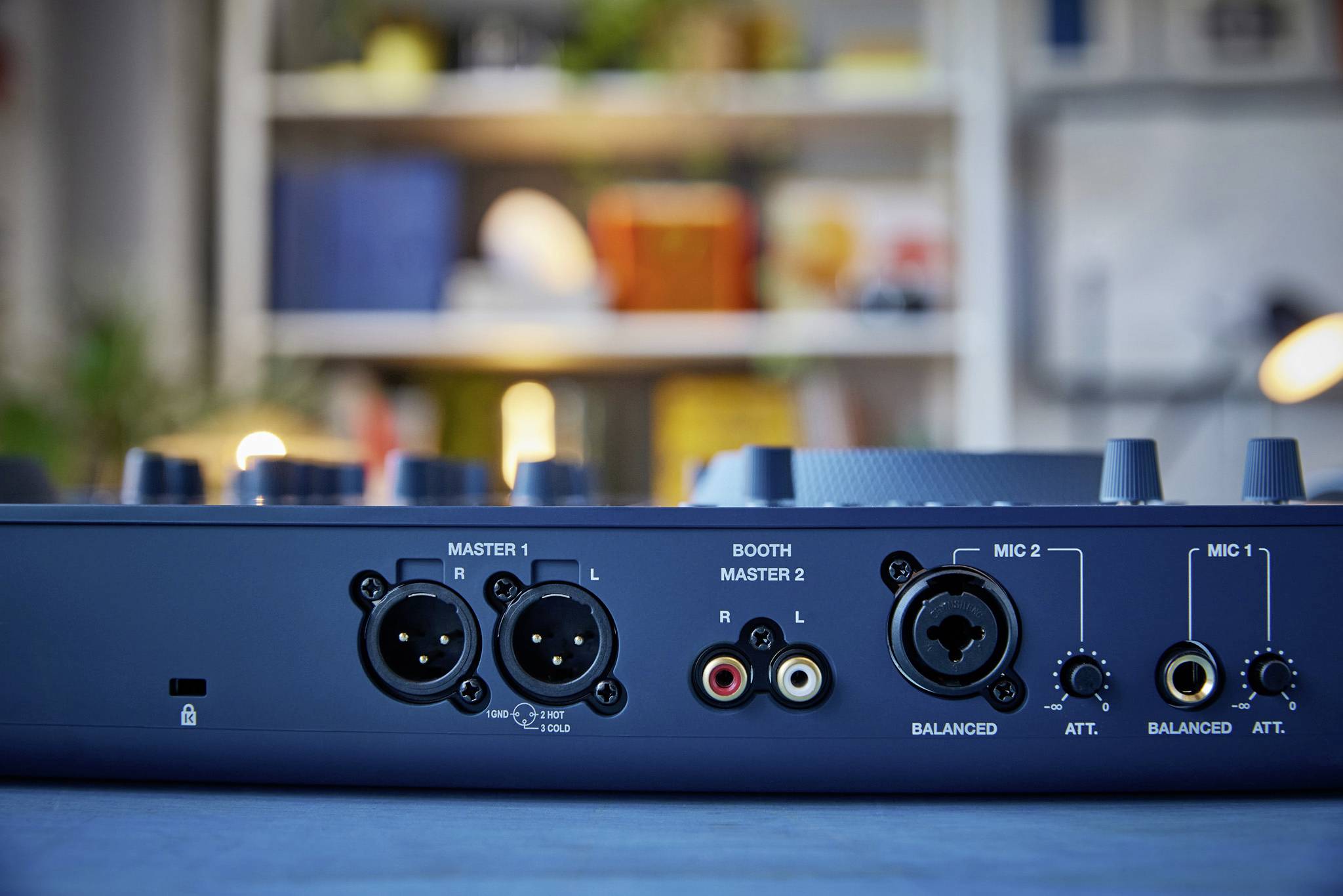 Back of an audio mixing desk with multiple XLR and jack inputs for microphones and speakers in a studio.