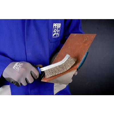 A person in blue workwear is cleaning a metal sheet with a wire brush.