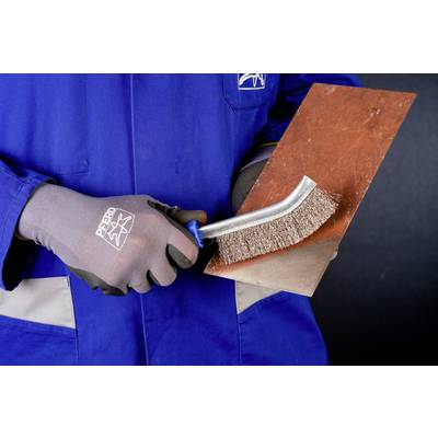 A person wearing blue workwear is cleaning rust from a metal plate using a steel brush.