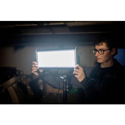 A person adjusts a bright studio light in a dimmed room.