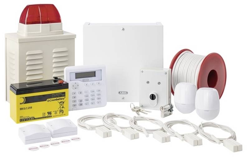 An alarm system kit with siren, control unit, keypad, cables, motion sensors and battery, ready for installation in a building.