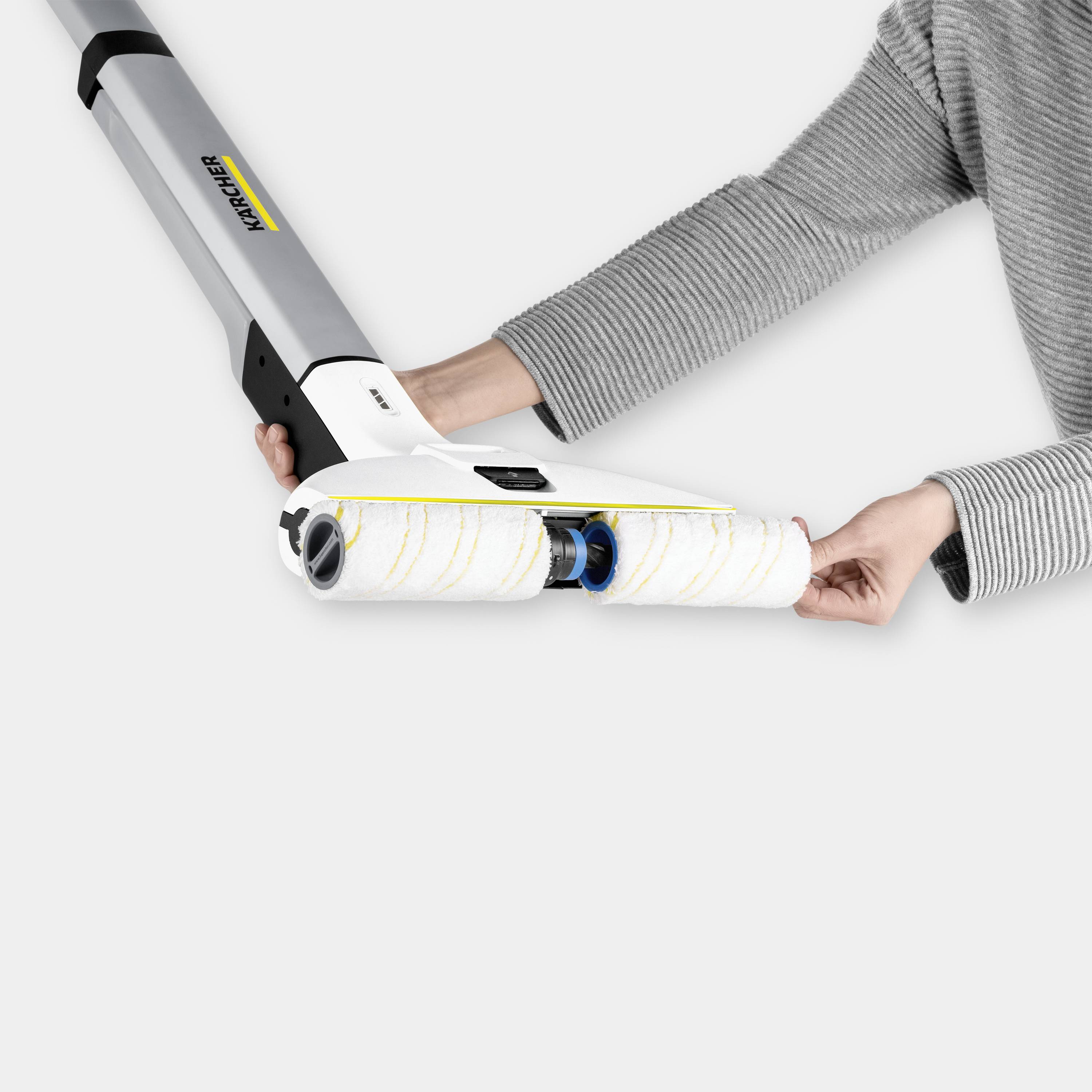 A person is holding an electric floor cleaner with rotating rollers, designed for efficient mopping.