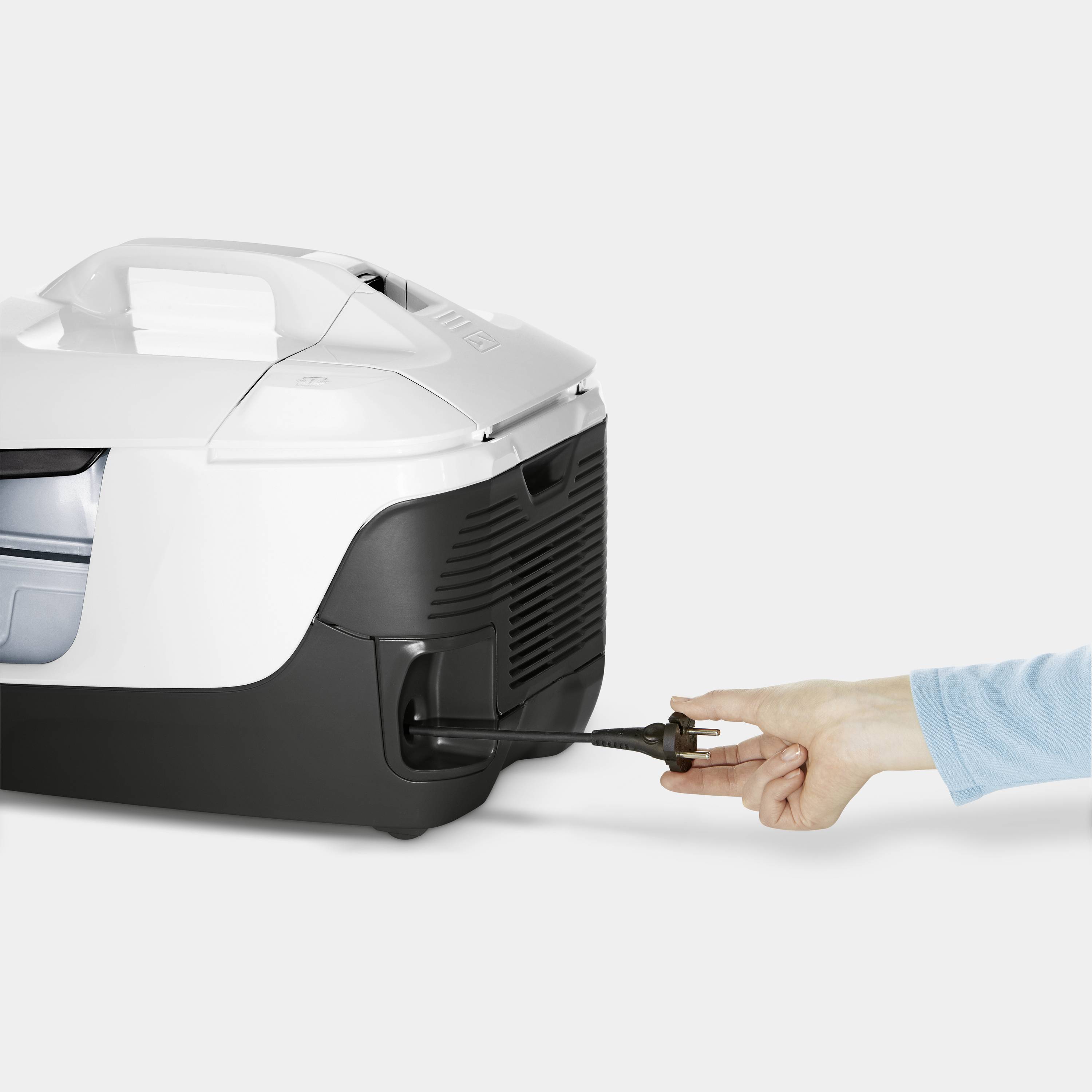 A person is holding a plug connection on a white and black device that looks like a container or a machine.