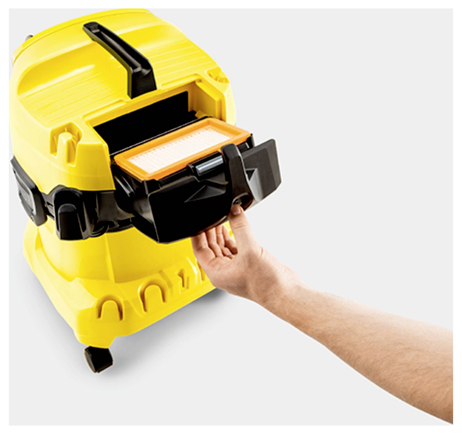 A person's hand removing the filter from a yellow vacuum cleaner, showing maintenance or cleaning process.