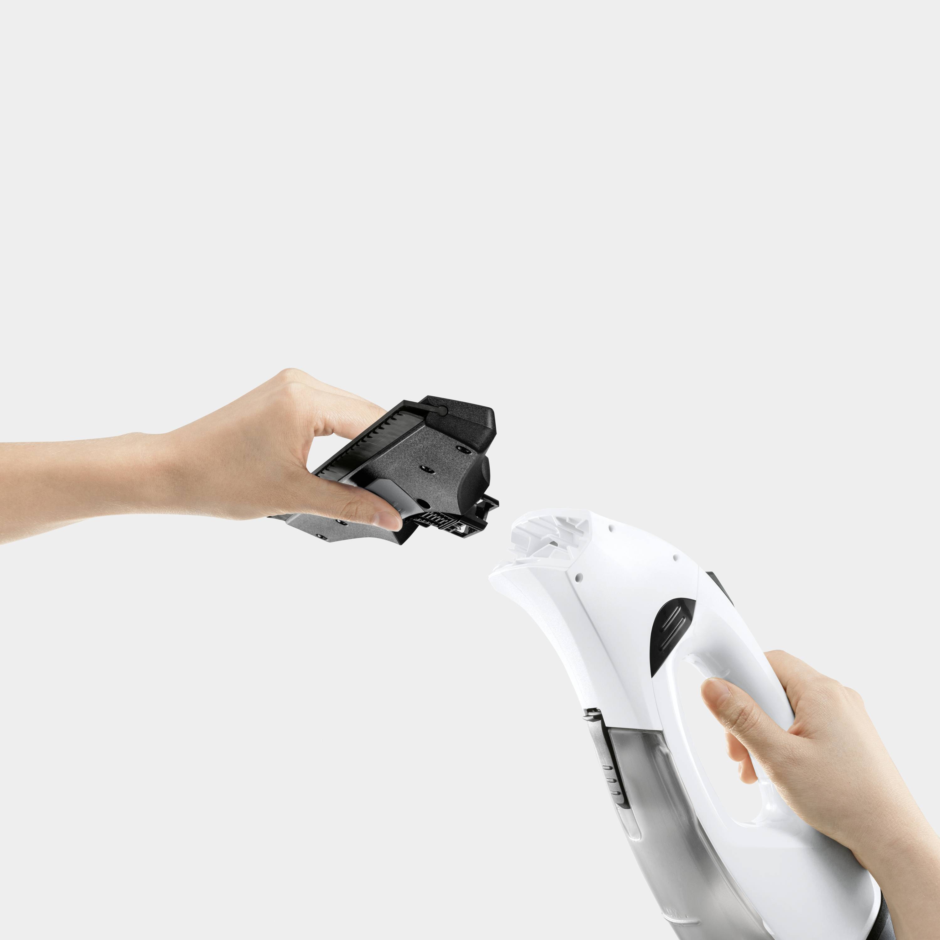 A hand is holding a black clip-on attachment part that can be fitted onto a white electric handheld razor.