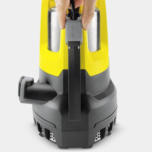 A hand is operating a black switch button on a yellow-and-black device that looks like a submersible pump.