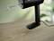 A black hand mixer sits on a wooden table; blurred plants are visible in the background.