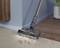 A vacuum cleaner head is sucking dirt from a carpet at the edge of a wooden floor.