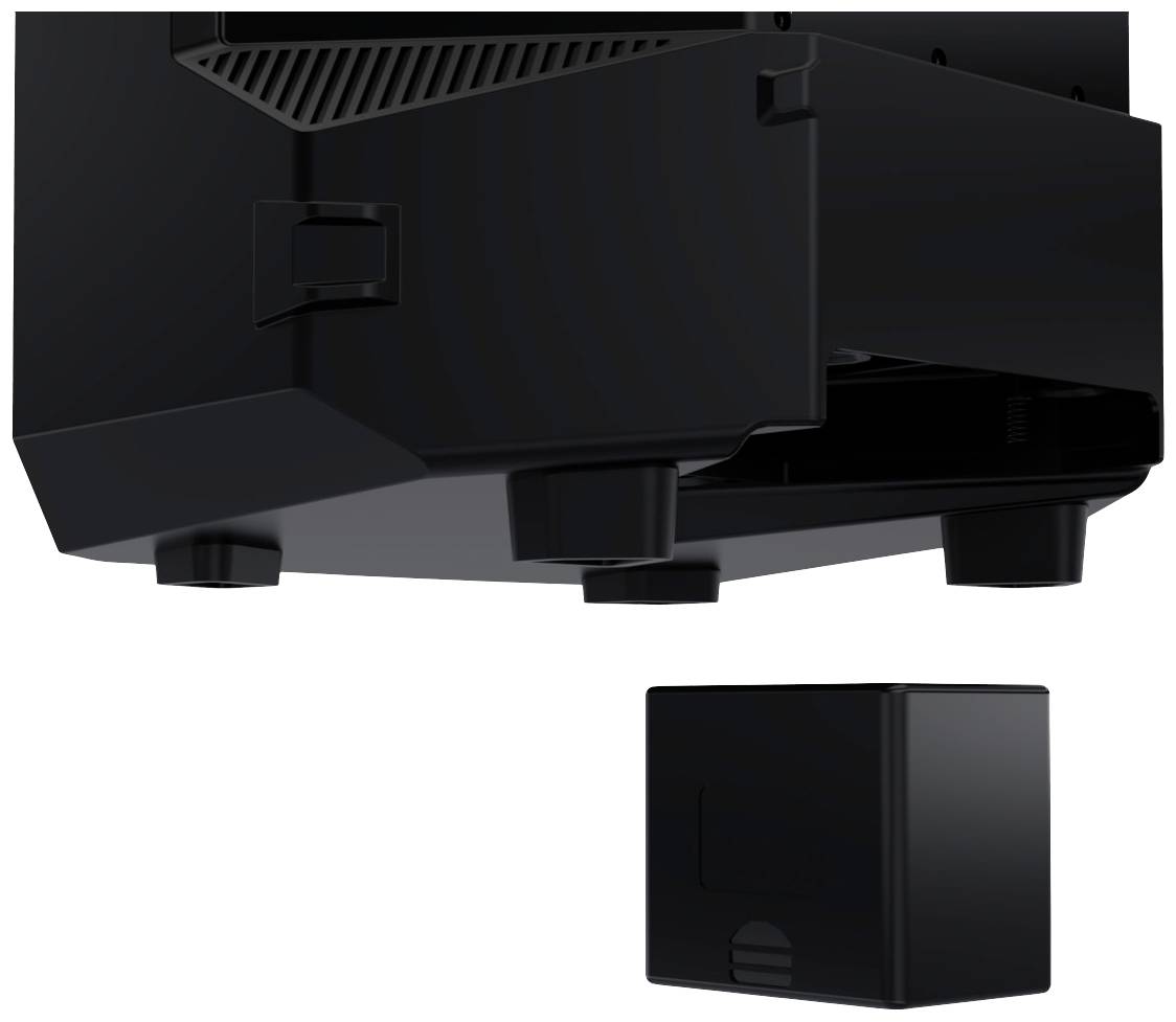 Low-angle view of a black device with visible stand feet. Beside it, a small cube, presumably an accessory.