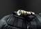 Torch lies on a black rucksack. The lamp is switched on and emitting light. The background is dark.