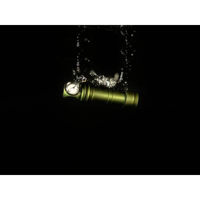 A green torch falls into water, bubbles rising. A dark background highlights the movement and brightness.