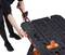 A person is using a bench vice to secure a workpiece on a work table. The table is black with orange details.