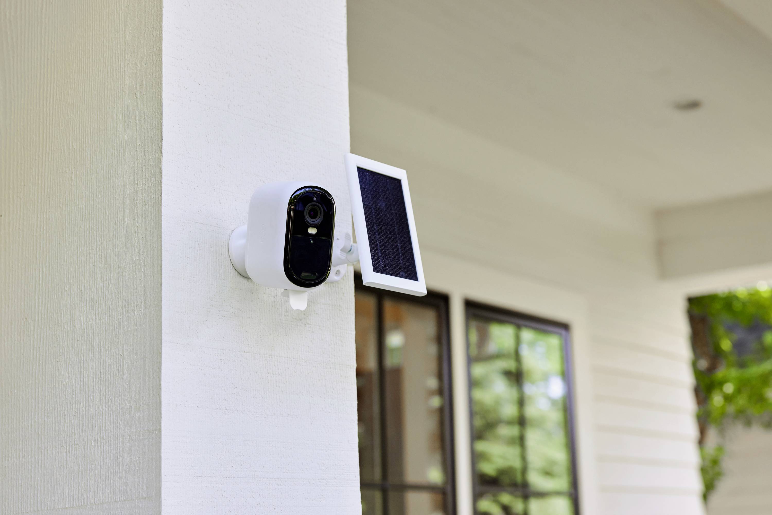 Security camera with solar panel installed on the wall of a modern house.