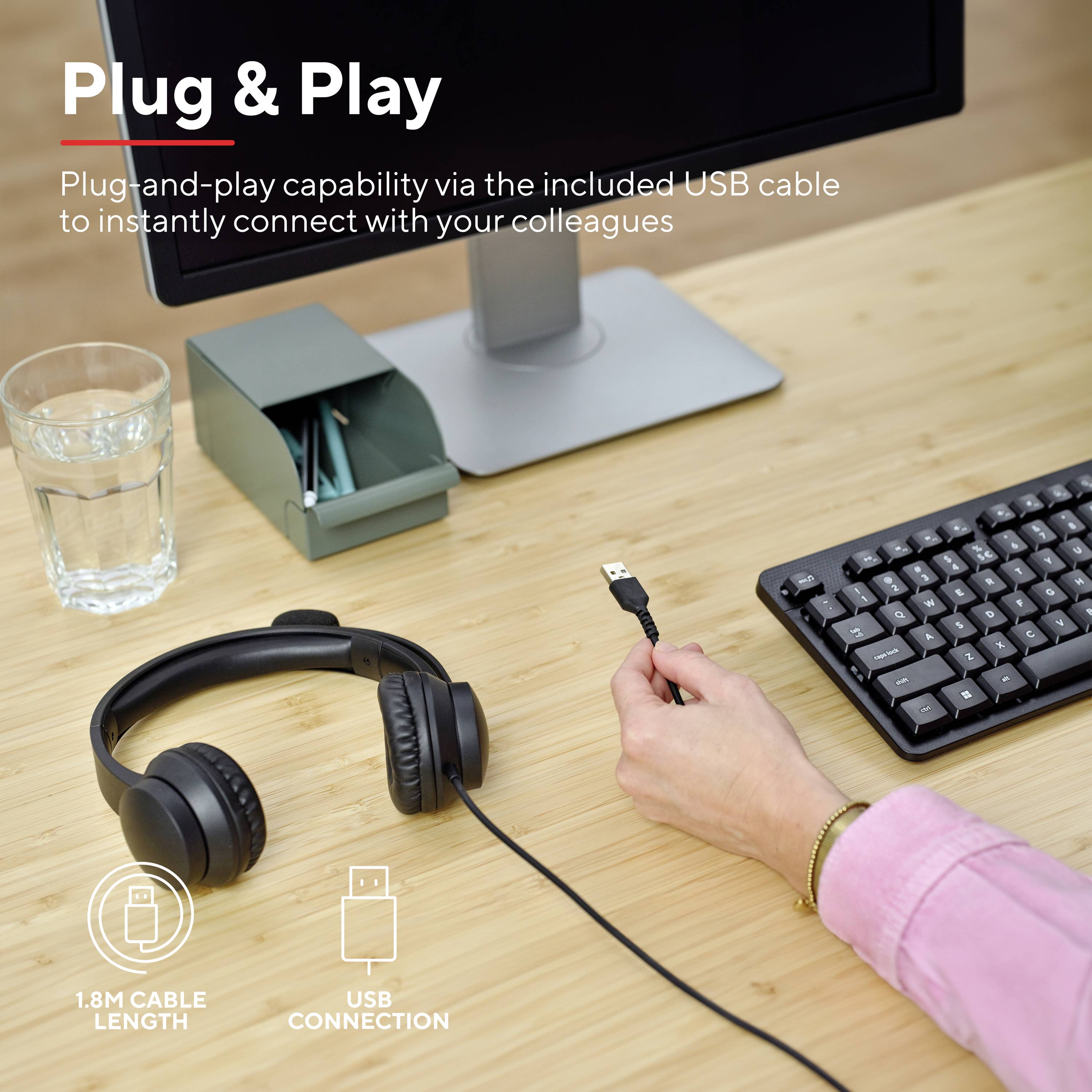 Plug and play device with USB cable, computer monitor, keyboard, headset and a hand about to connect the cable.