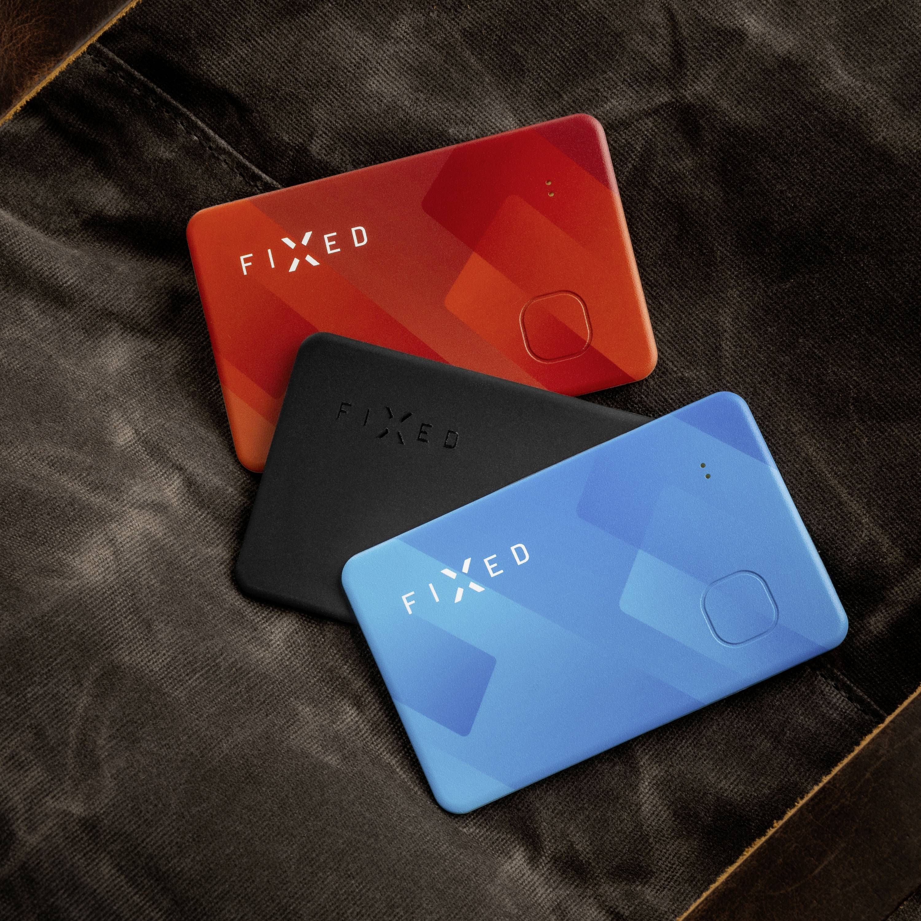 Three coloured replacement cards, red, black and blue, are lying on brown fabric. On each card is written 'FIXED'.