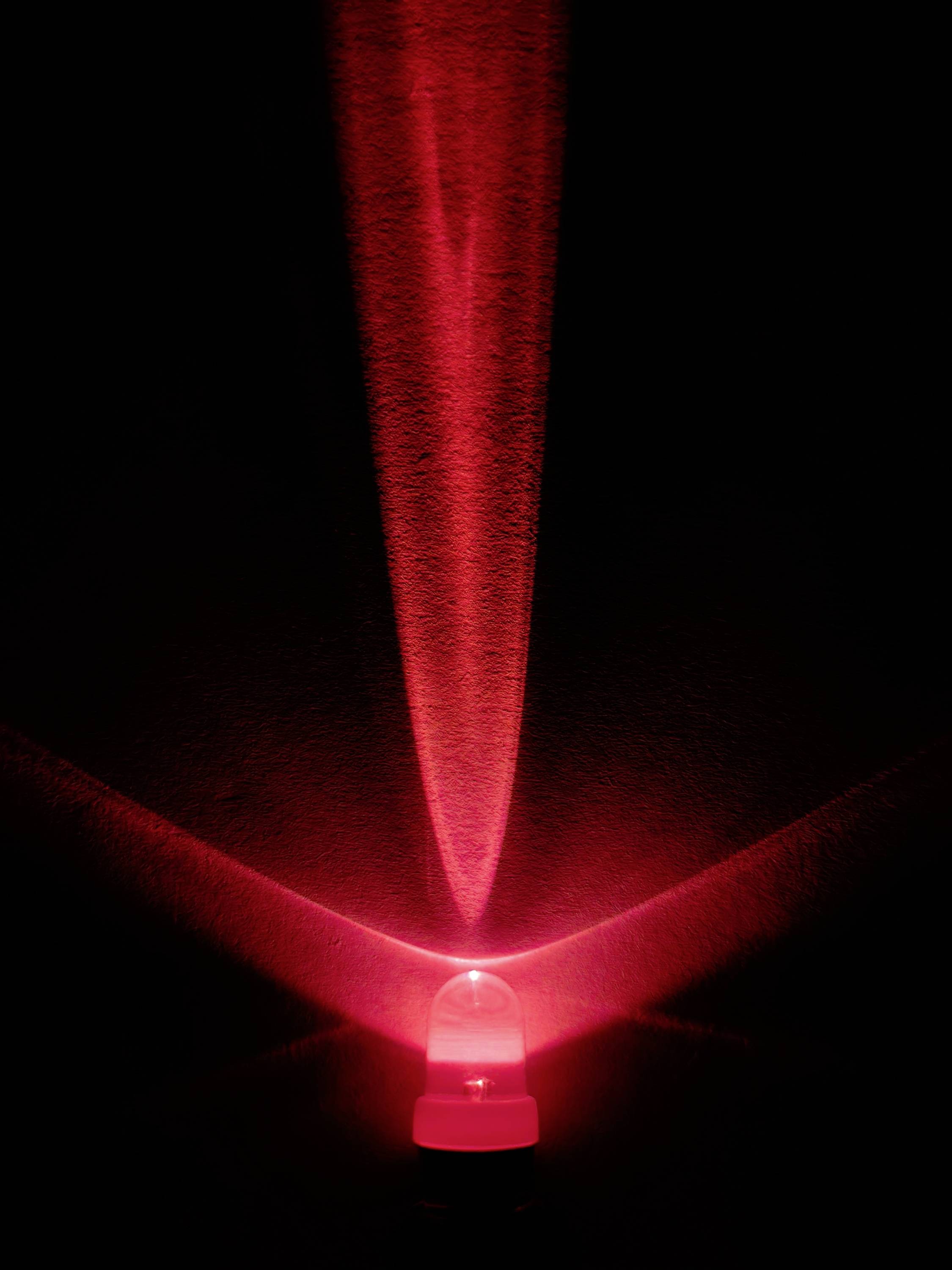 Glowing red LED in the darkness, casting a V-shaped light pattern onto a black surface.