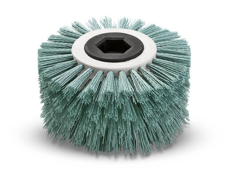 A round brush with greenish bristles and a black hexagonal hole in the centre, suitable for cleaning purposes.